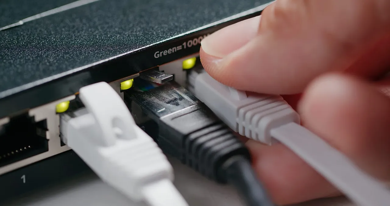 Photo en zoom d'une main branchant un câble sur un routeur Ubiquiti Edgerouter.