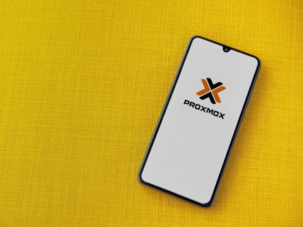 Photo d'un smartphone sur une nappe jaune avec l'application Proxmox à l'écran.