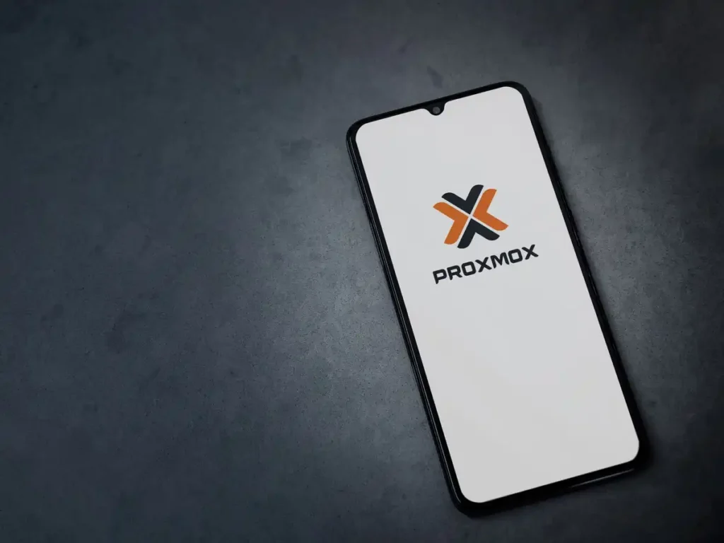 Smartphone sur une table noire avec l'application Proxmox VE 9.2 à l'écran.